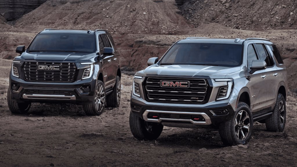 2025 GMC Yukon Denali and Yukon AT4 parked side by side on rugged terrain in desert canyon