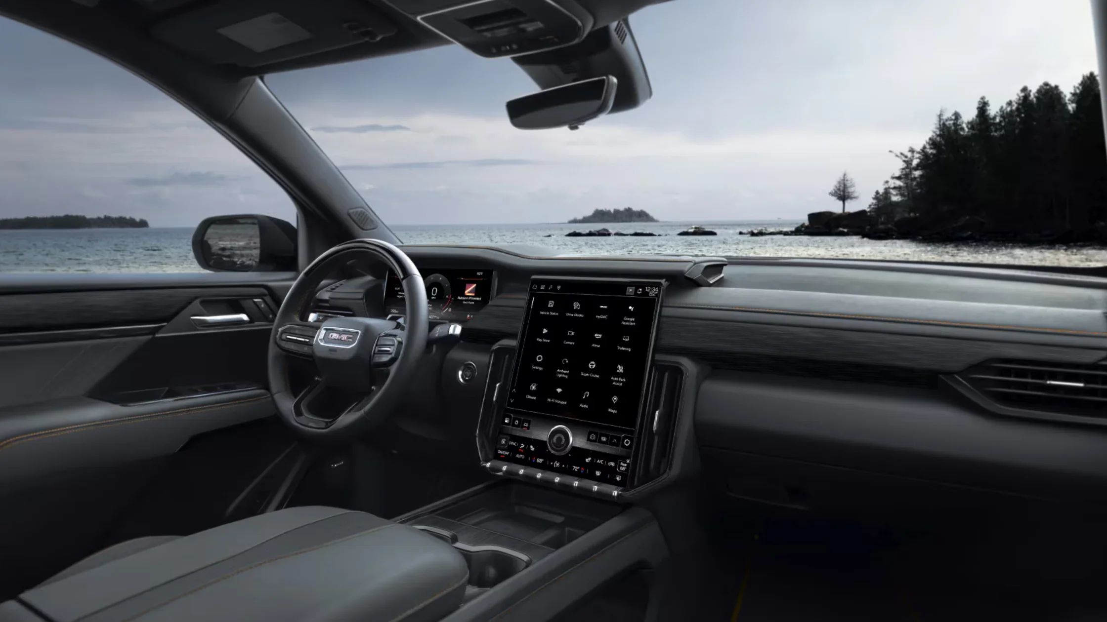 2025 GMC Acadia dashboard with large center touchscreen and digital gauge cluster, ocean view behind