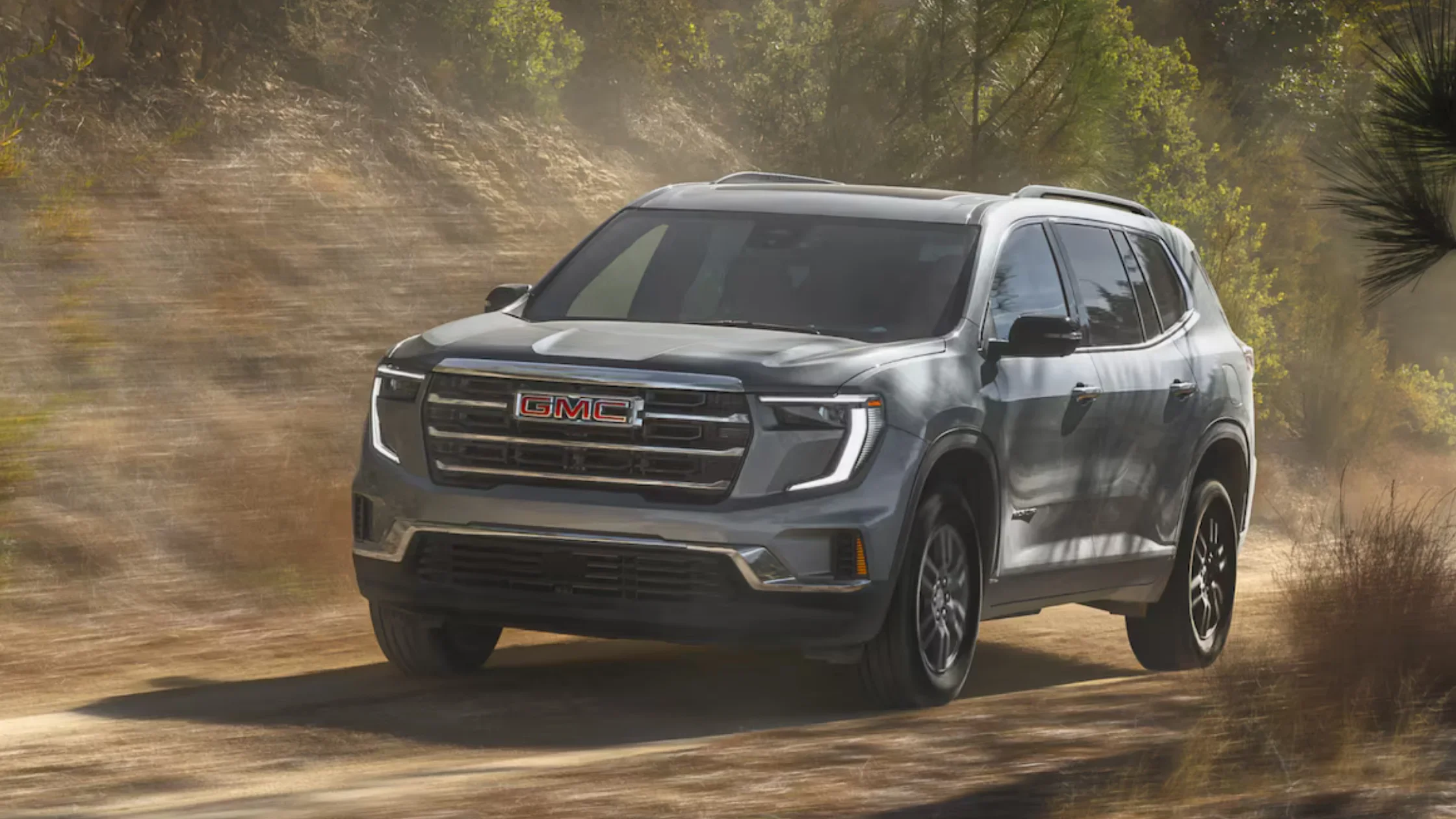 Front view of silver 2025 GMC Acadia driving off-road through dirt trail near Dickson, TN