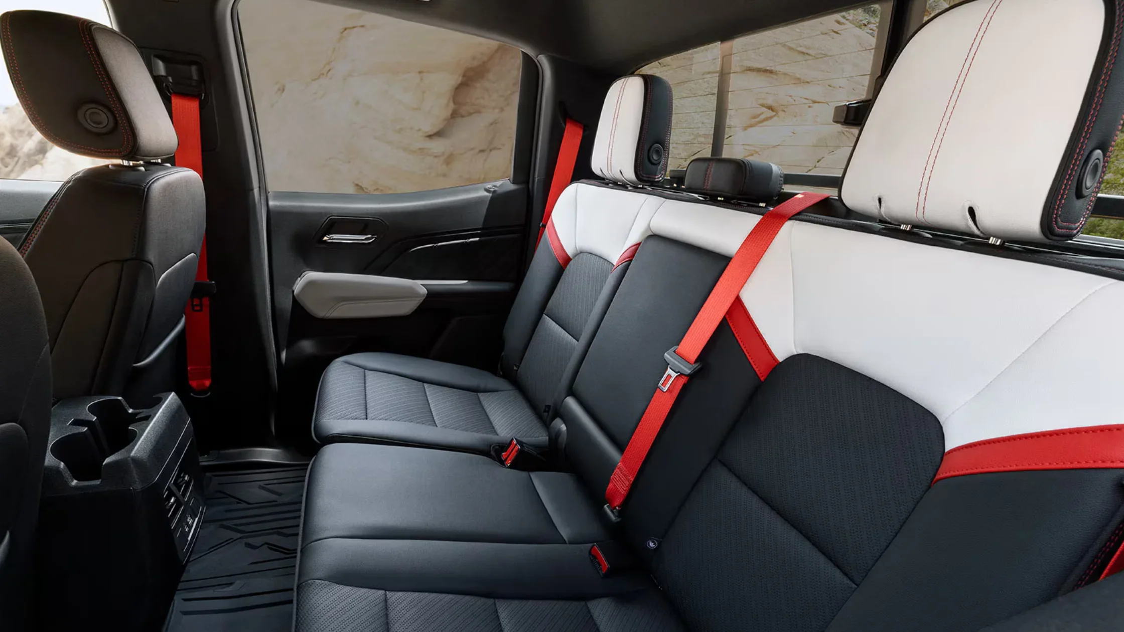 2025 GMC Canyon rear seat view with two-tone black and white leather and red seat belts