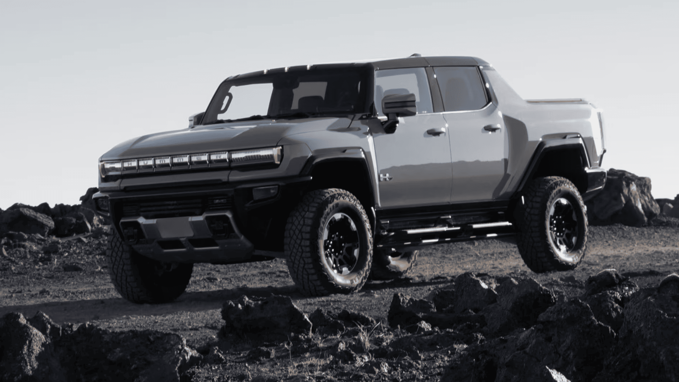 2025 GMC Hummer EV Pickup parked on rocky terrain with aggressive off-road tires.