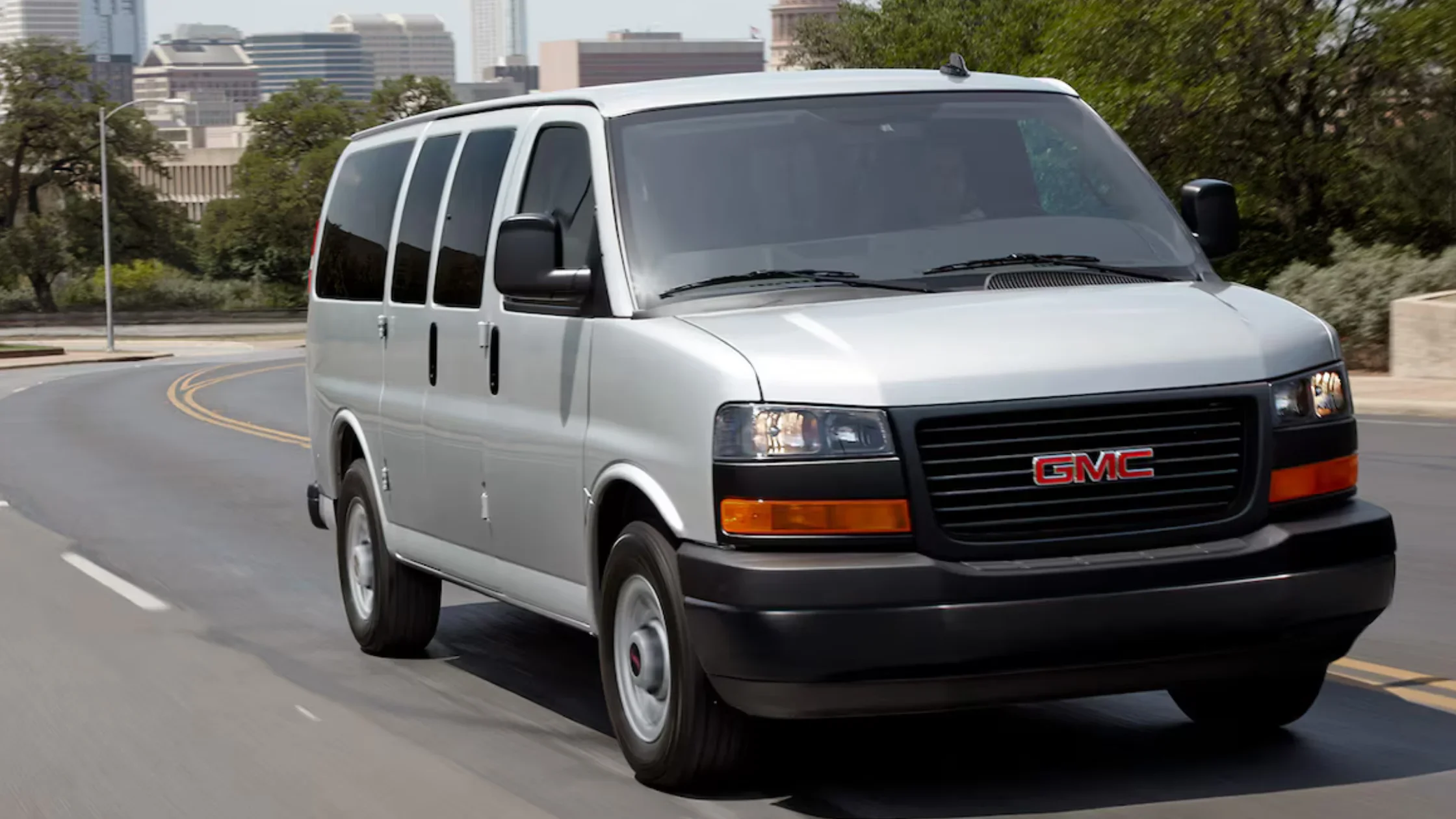 Front view of the 2025 GMC Sierra 3500 HD AT4, featuring bold grille, C-shaped LED lights, and rugged stance in a desert landscape.