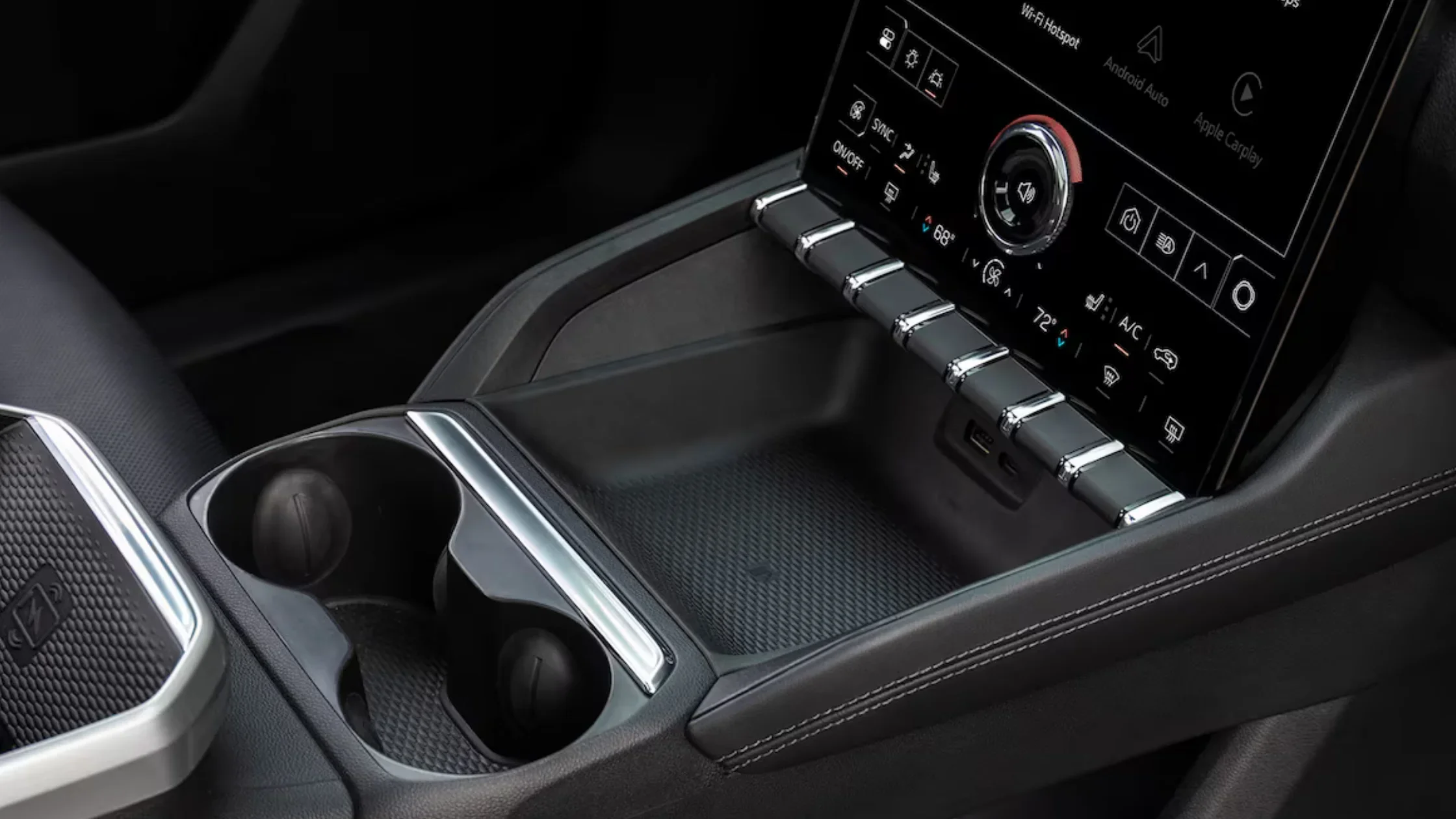 Close-up of center console in 2025 GMC Terrain with chrome toggles, cupholders, and touchscreen.