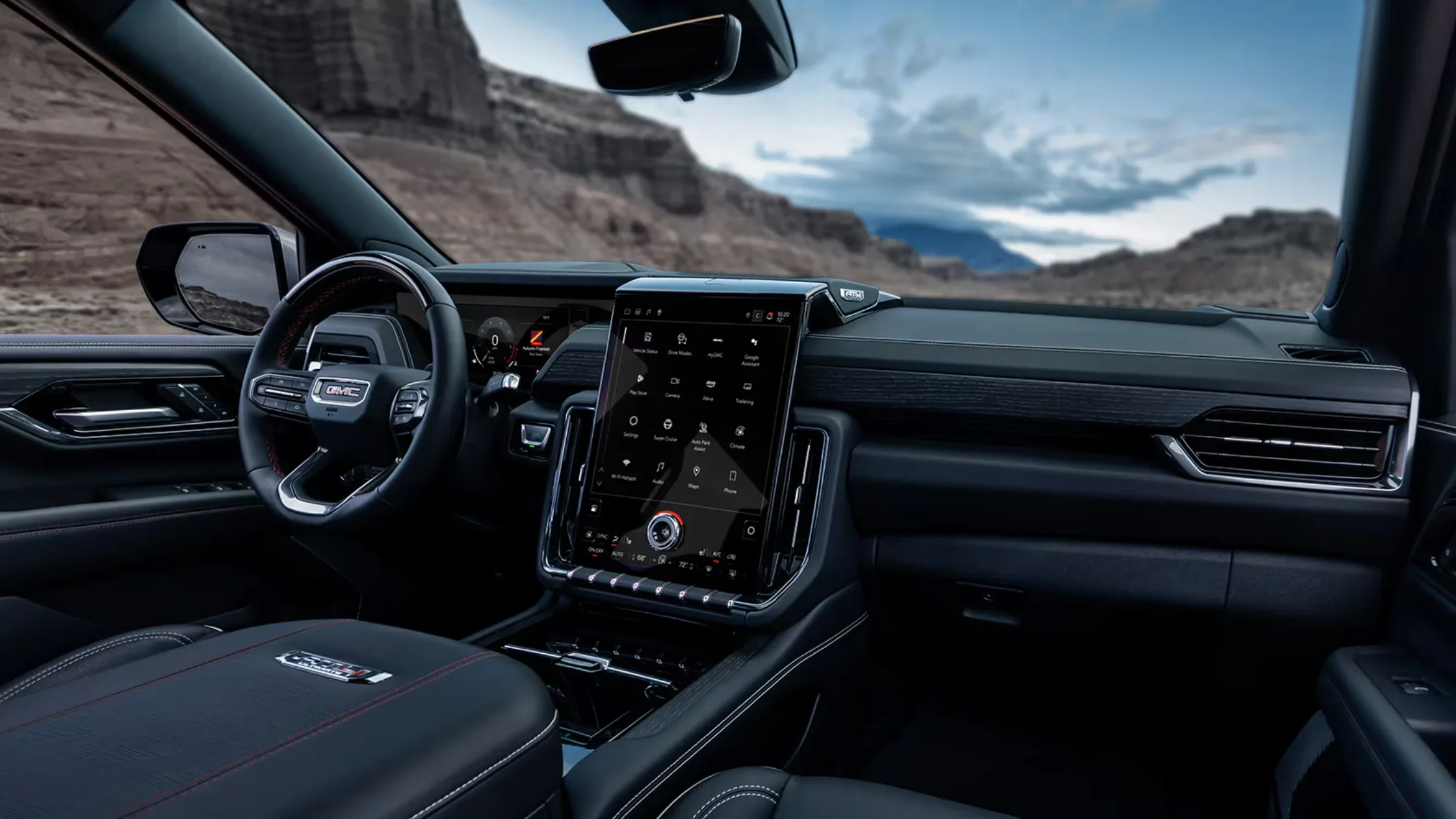 Driver-side view of the 2025 GMC Yukon XL interior, highlighting the digital gauge cluster, large vertical touchscreen infotainment system, and black leather dashboard with red stitching.