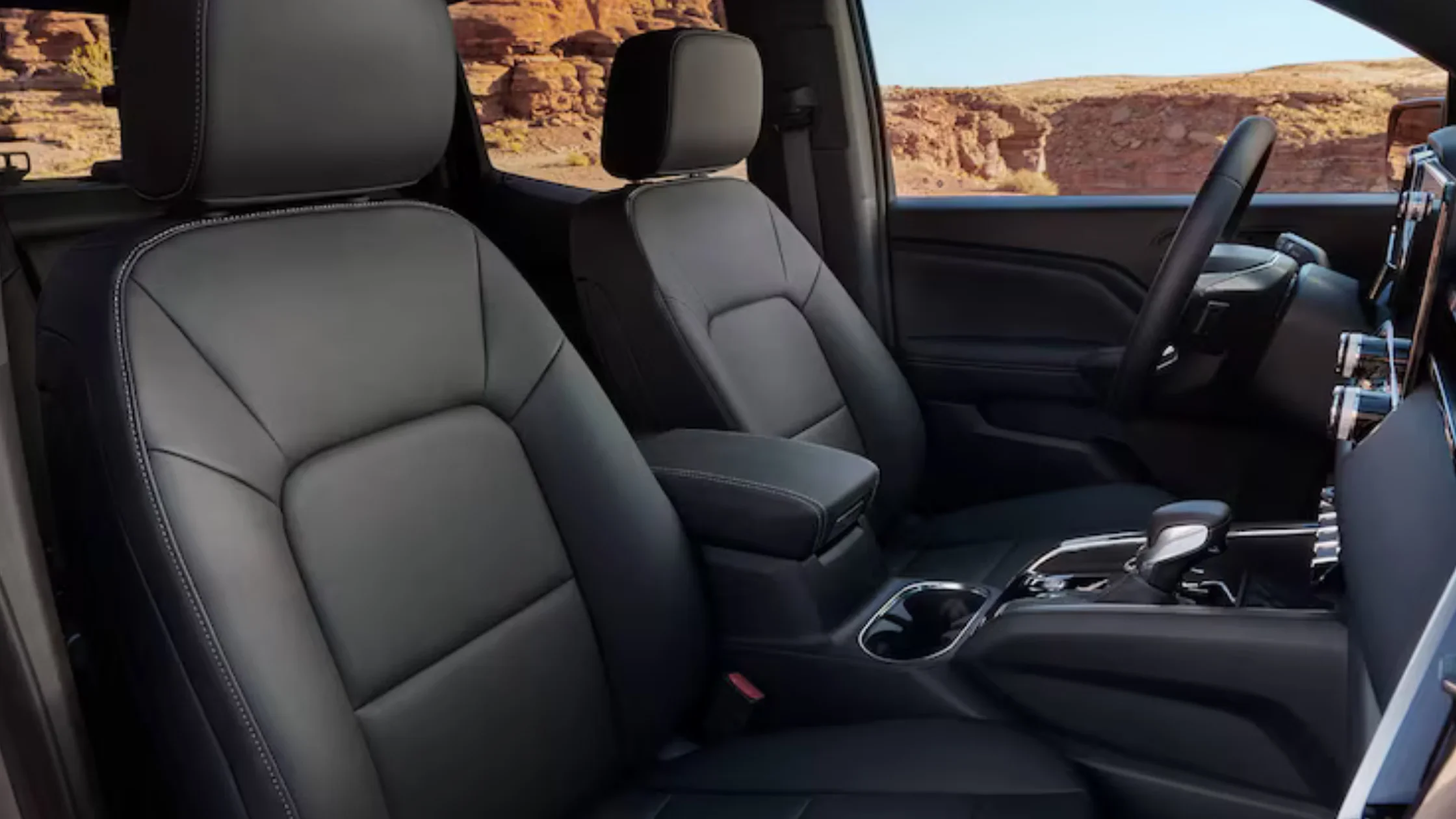 2026 GMC Canyon interior view showing black leather seats with contrast stitching and center console.