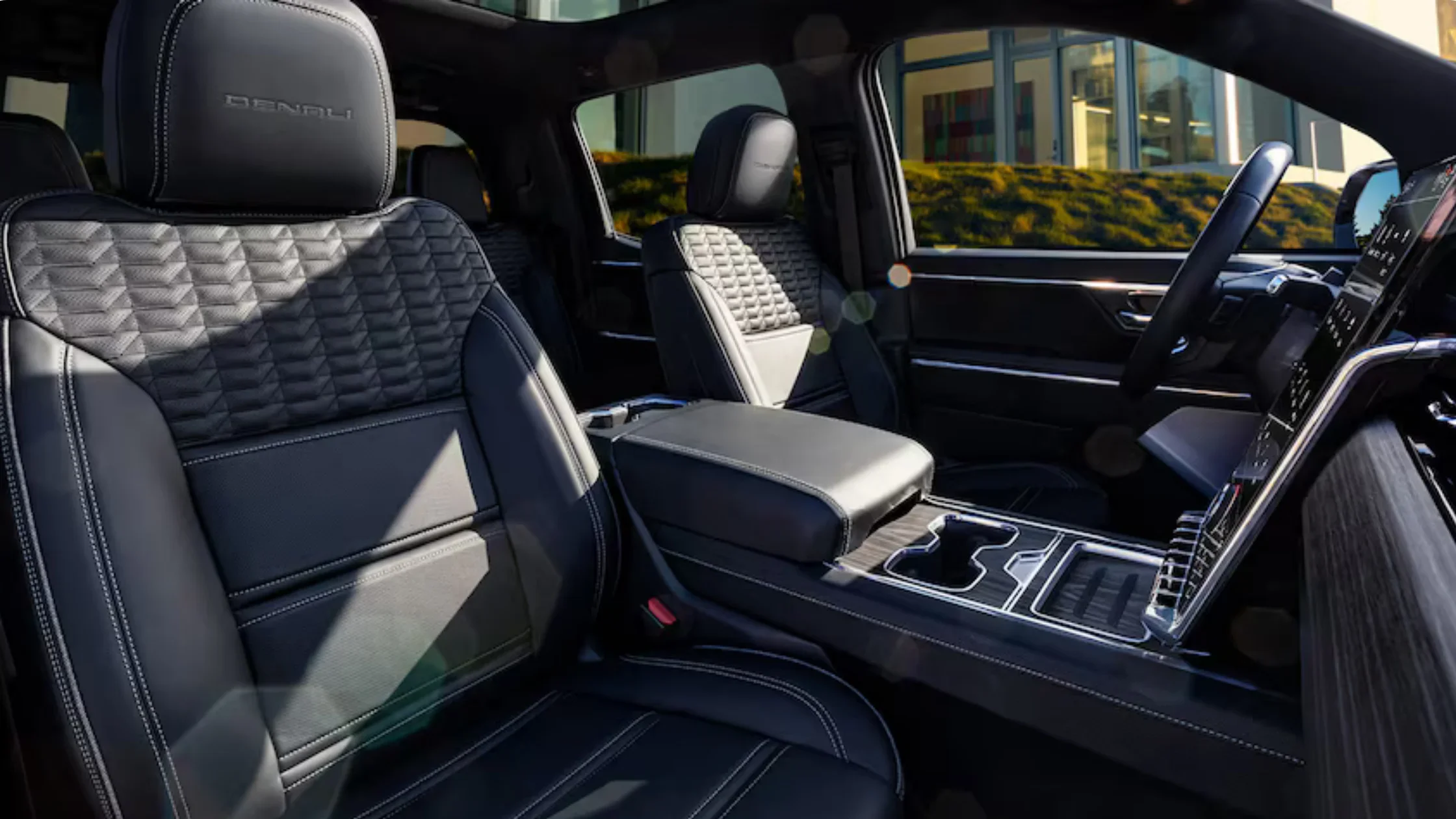 Front seats of 2026 Sierra EV Denali with quilted leather design and center console.